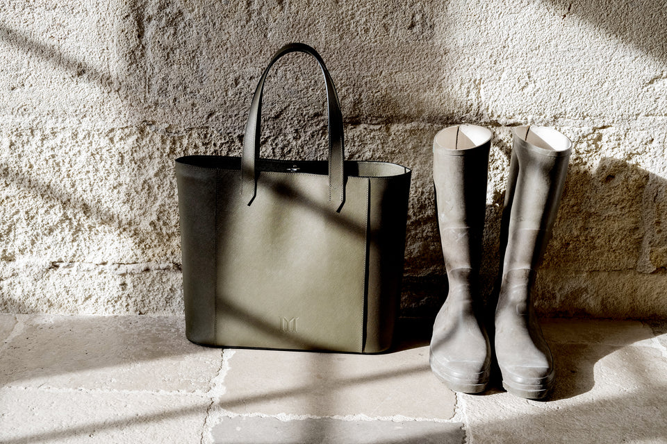 Maison Marrain DeuxVin Bag in vine green and rubber boots against a stone wall