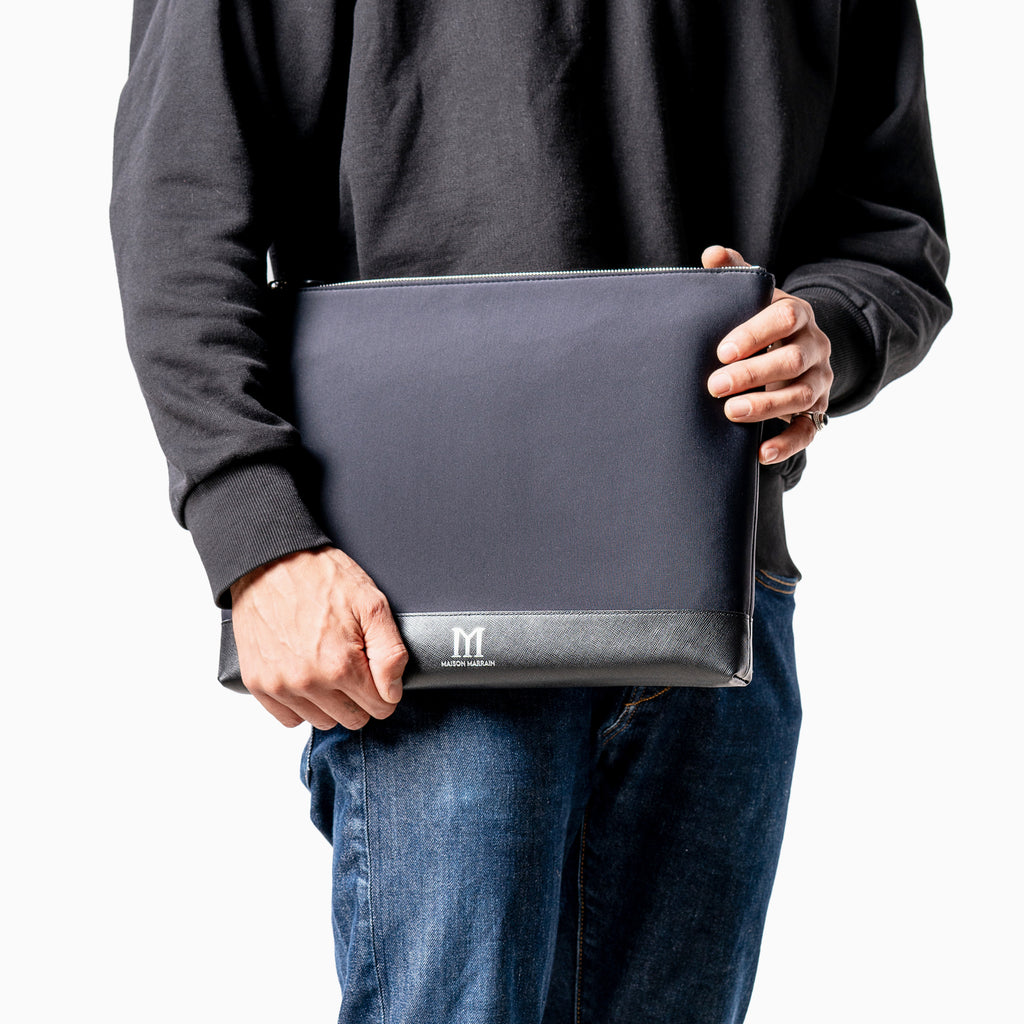 man holding Maison Marrain deux vie large black pouch for laptop or documents made from neoprene with durable leather trim in black