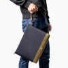 man holding Maison Marrain deuxvie large black pouch for laptop or documents made from neoprene with durable leather trim in vine green with strap