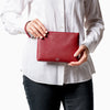 femme tenant une petite pochette Maison Marrain DeuxVie en cuir rouge bordeaux avec anse