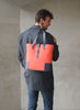 elegant Man holding the DeuxMag All Weather big neoprene and leather mandarin and blue Tote bag 