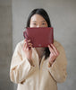 asian woman holding Maison Marrain DeuxVie petite pochette bordeaux en cuir rouge avec bandoulière