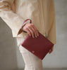woman holding Maison Marrain DeuxVie small leather red Bordeaux pouch with strap