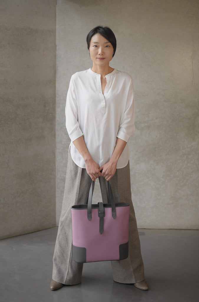 Asian woman holding the DeuxMag All Weather big neoprene and leather rose and grey Tote bag 