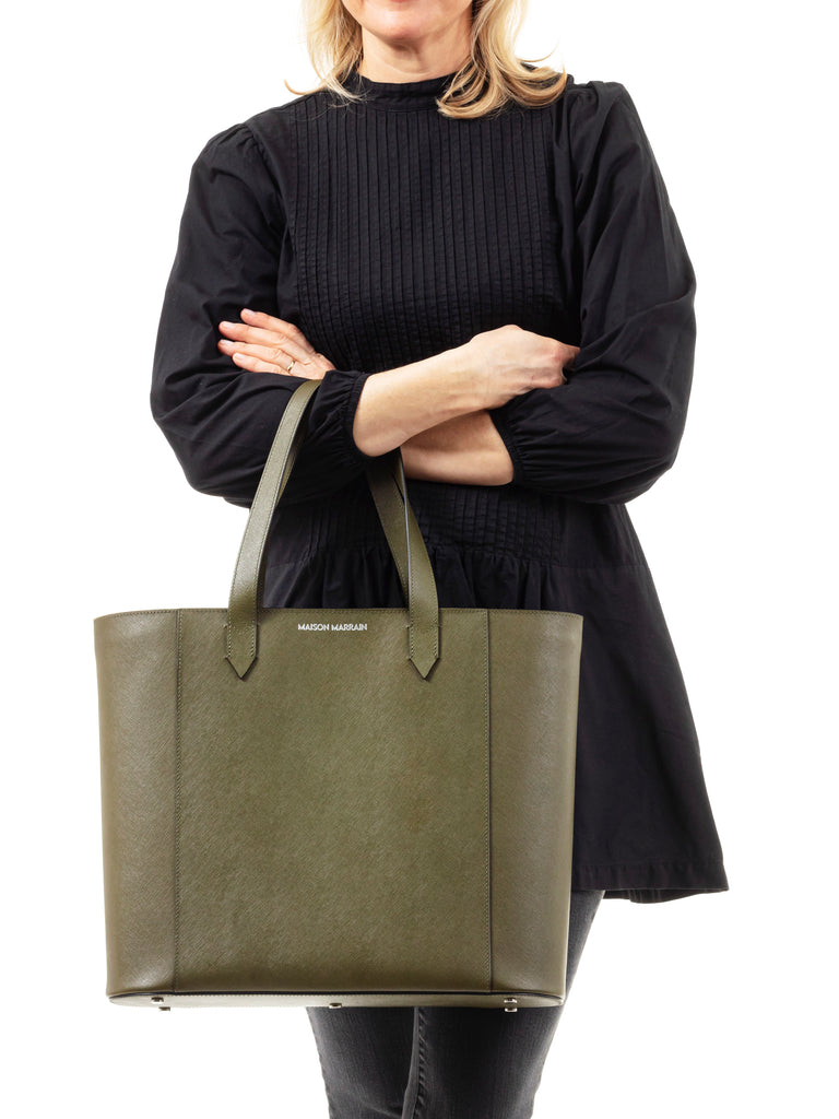 woman in black holding a Maison Marrain DeuxVin leather tote Bag in vine green