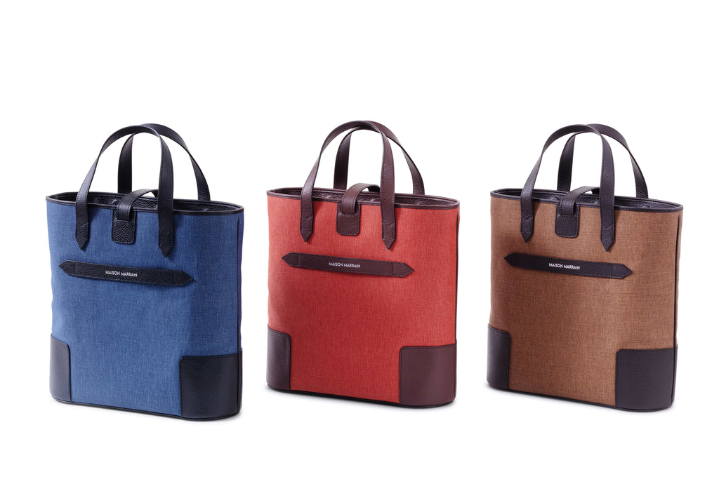 Back of three Deuxmag tote bags in blue red and brown