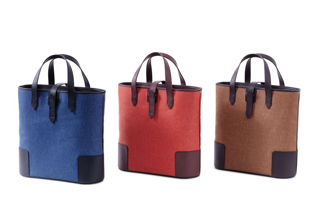  Front of three Deuxmag tote bags in blue red and brown