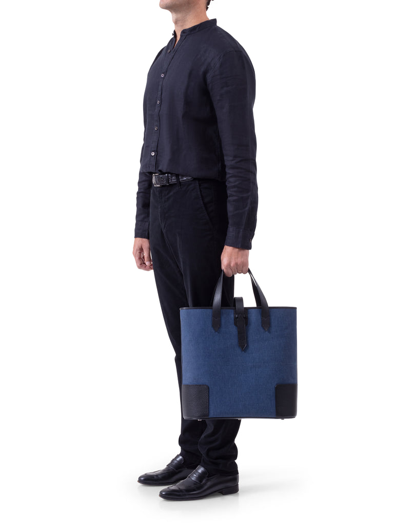 Man holding the DeuxMag  big canvas and leather blue marine and black Tote bag 