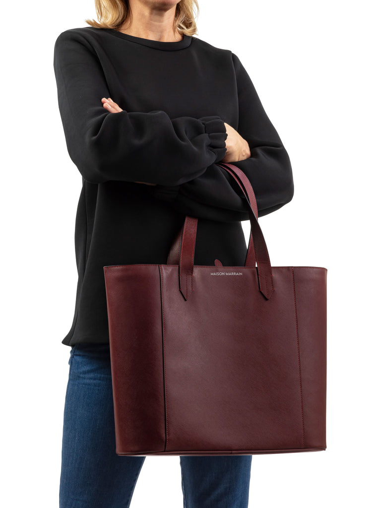 woman with crossed arms holding Maison Marrain DeuxVin leather tote Bag in red bordeaux